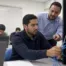 it student sitting at table in class working on a network server while an instructor explains the lesson